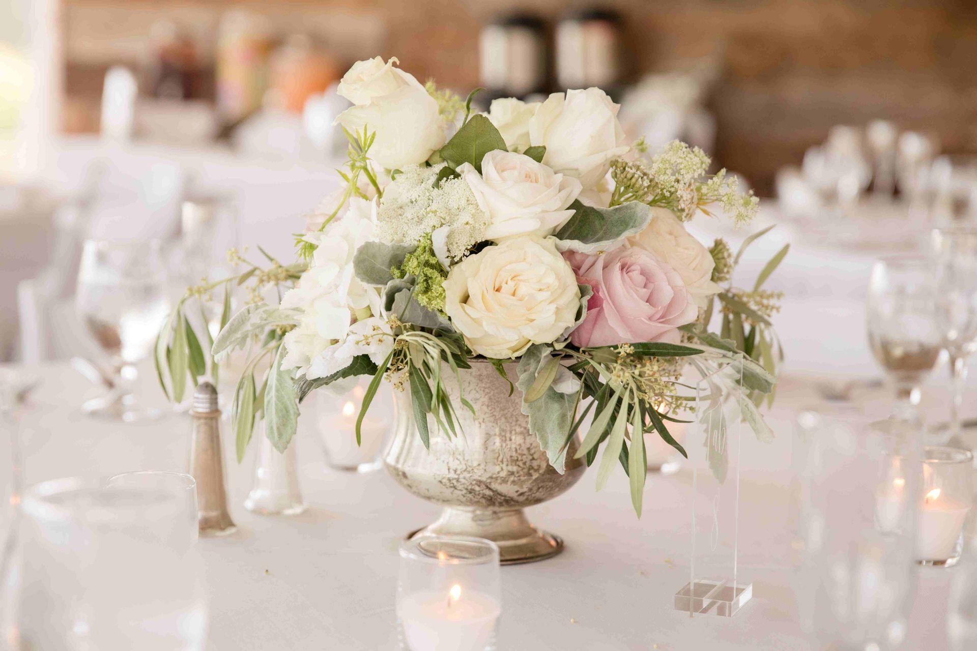 A vase filled with white flowers and a candle on a table.
