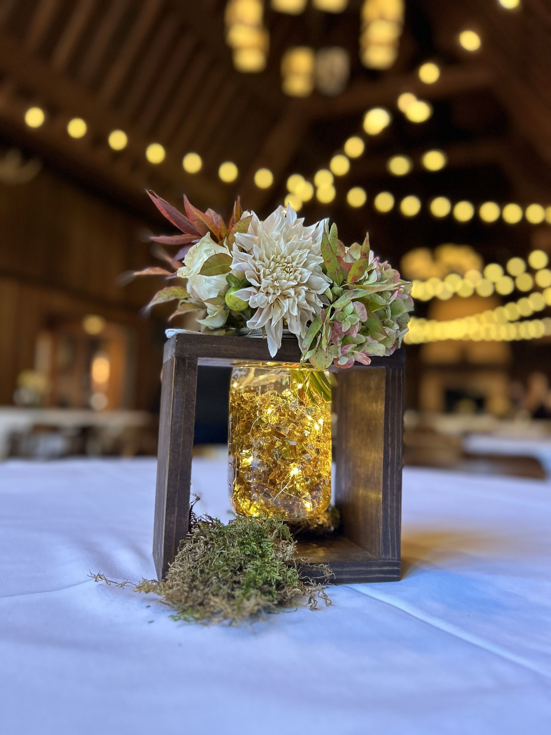 A wooden box filled with flowers and lights is sitting on a table.