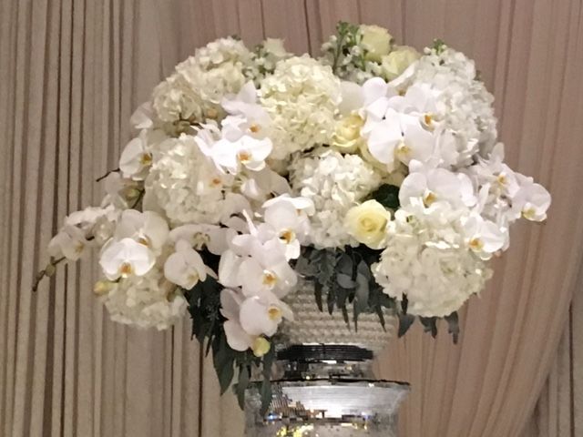White floral arrangement: hydrangeas, orchids, and roses in a silver pedestal vase.