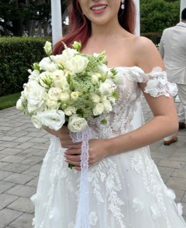 A woman in a wedding dress is holding a bouquet of white flowers