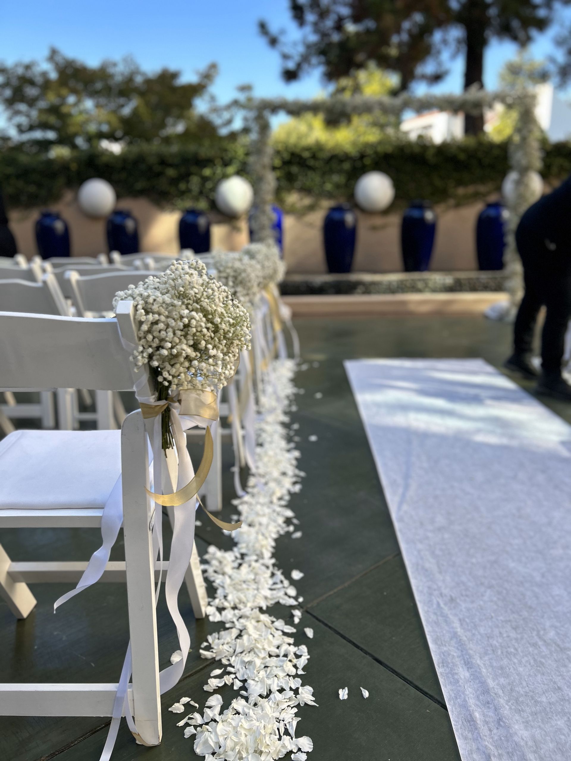A wedding aisle decorated with baby 's breath bouquets and petals