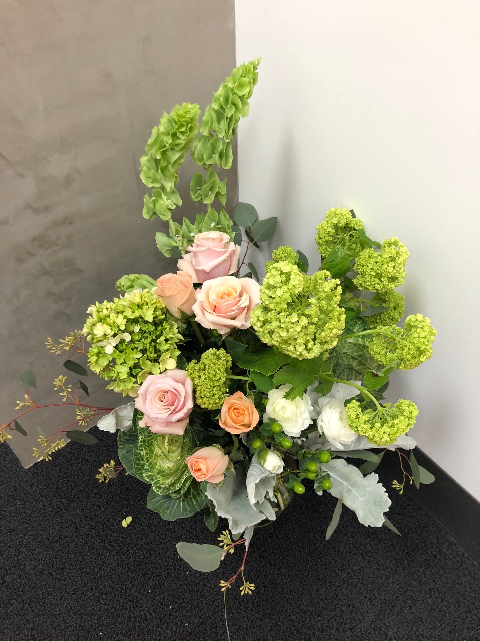 A bouquet of flowers is sitting on a table next to a wall.