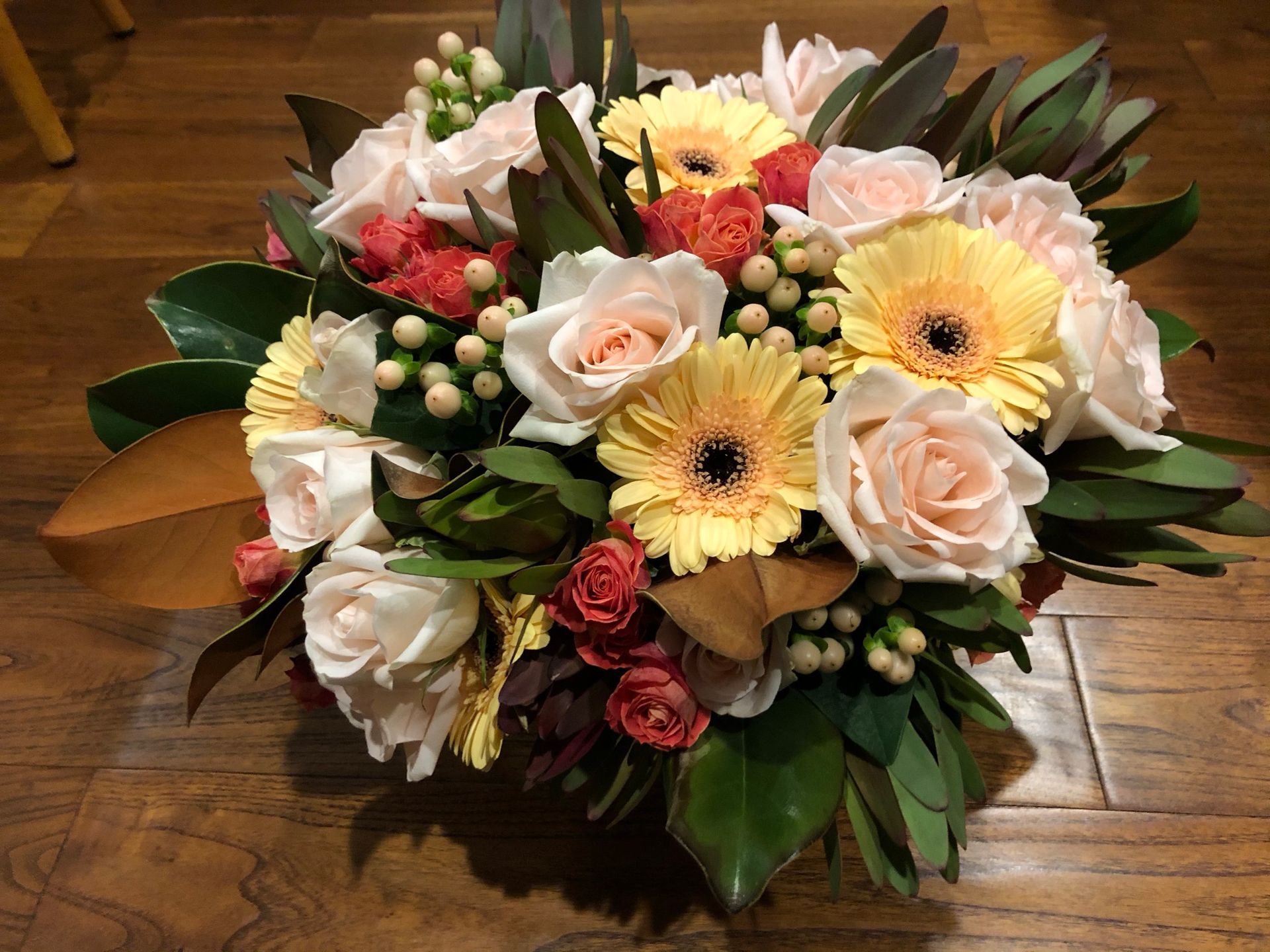 A bouquet of flowers is sitting on a wooden table.