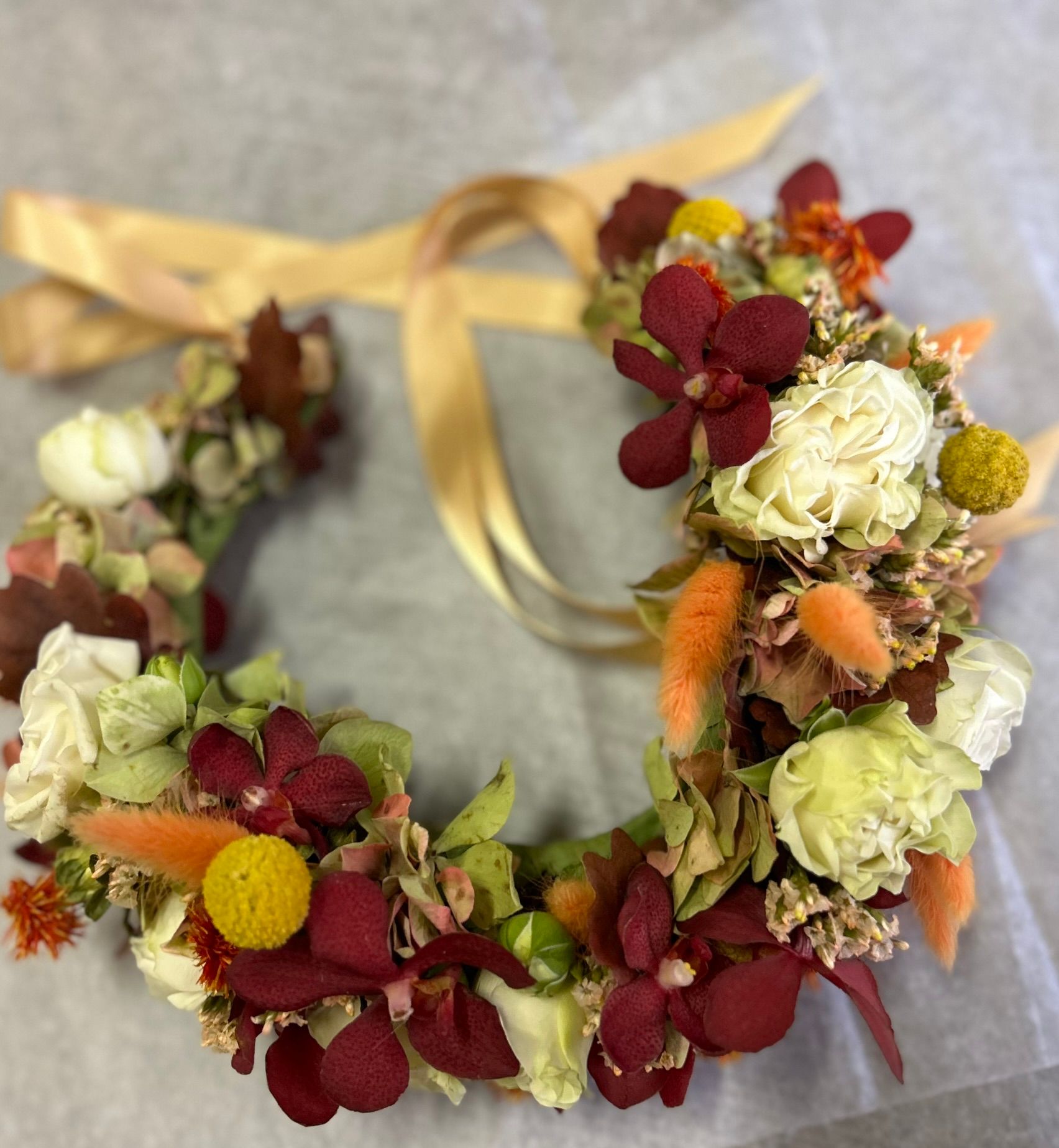A wreath of flowers is tied with a gold ribbon