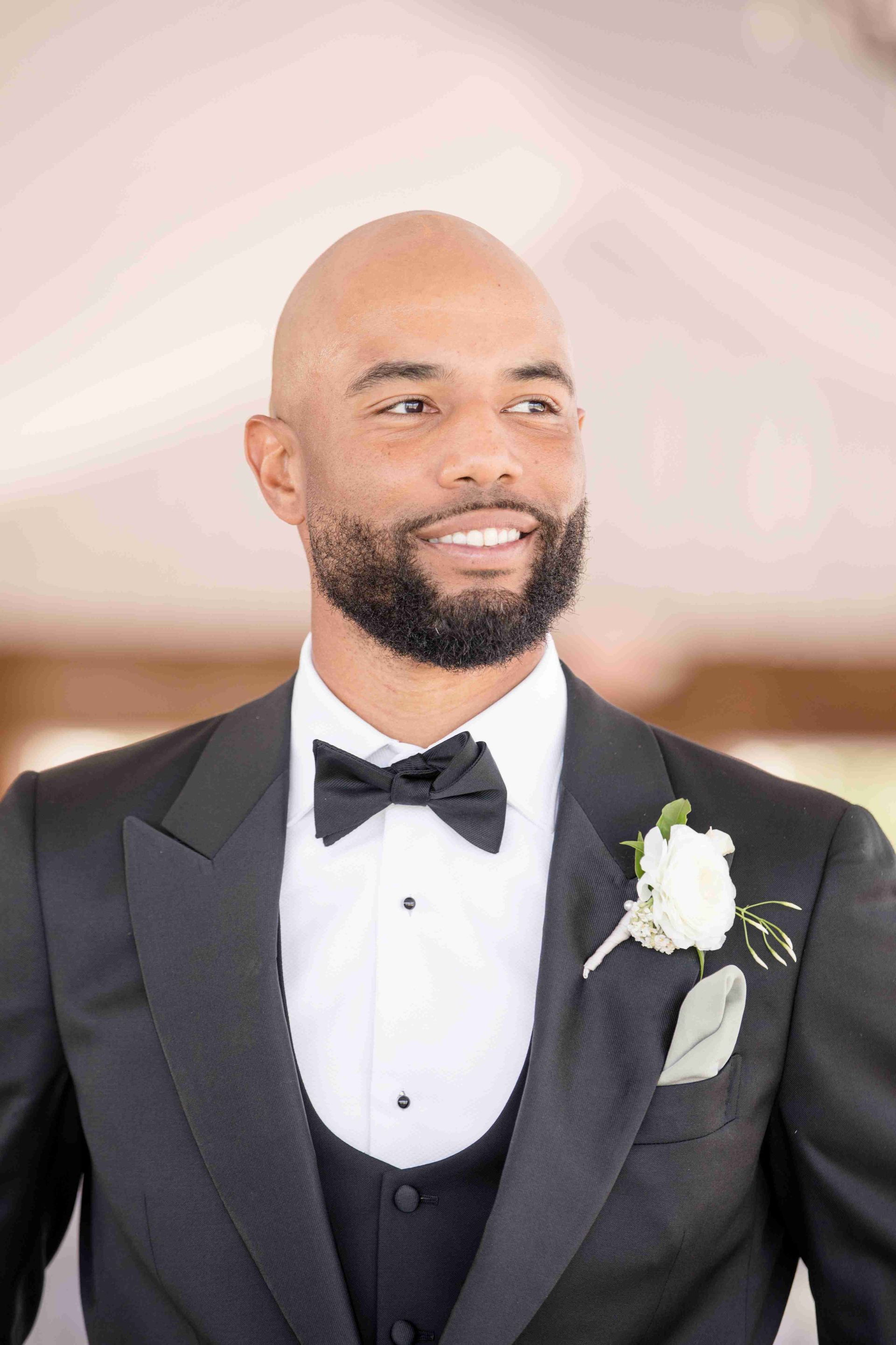A man with a beard is wearing a tuxedo and bow tie.