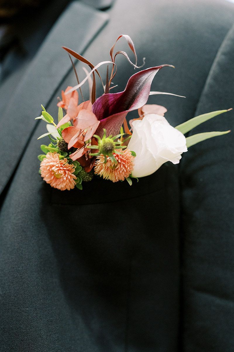 A close up of a buttonhole with flowers on a suit jacket.