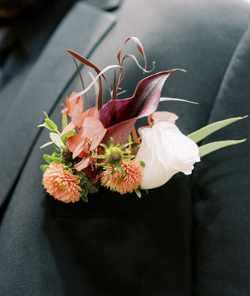 A close up of a buttonhole with flowers on a man 's jacket