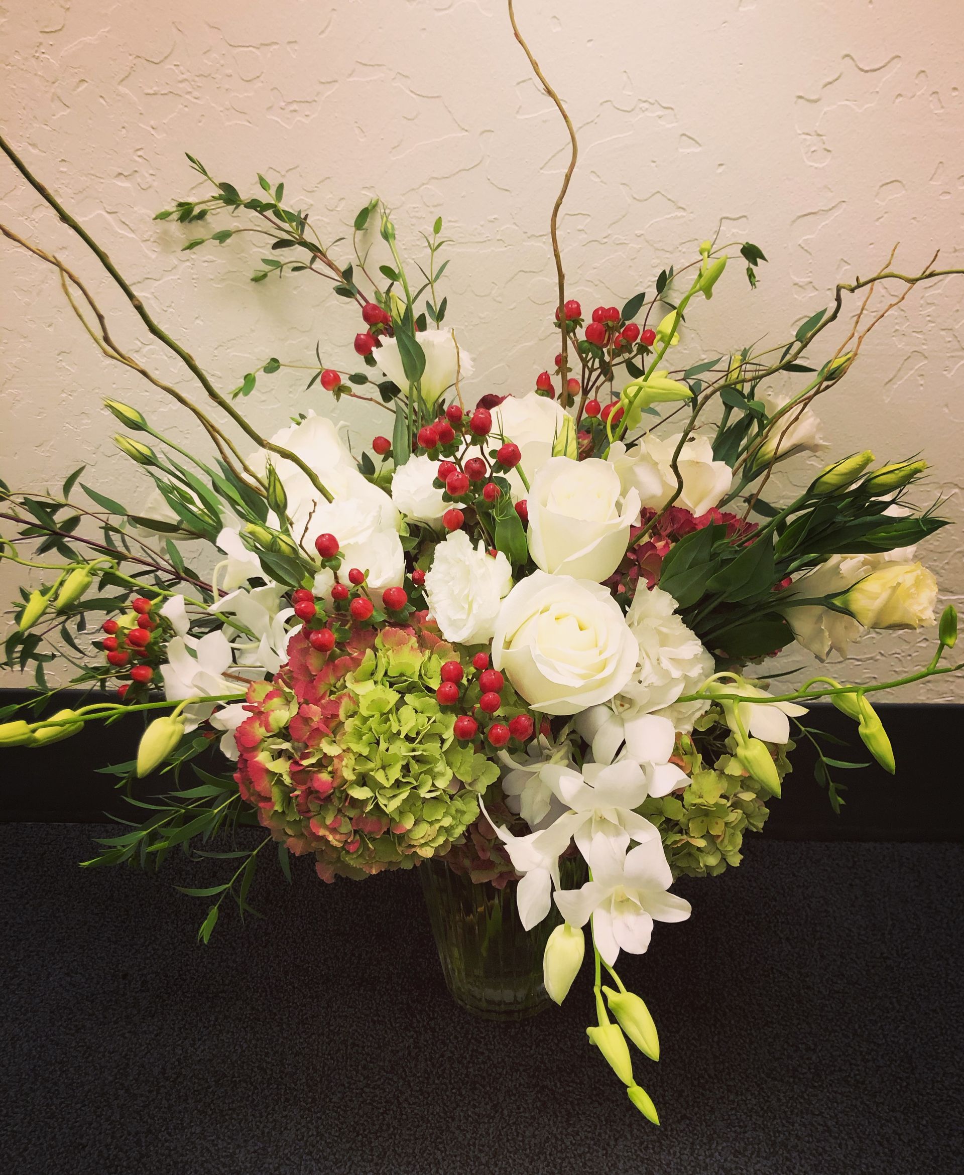 A vase filled with white flowers and red berries