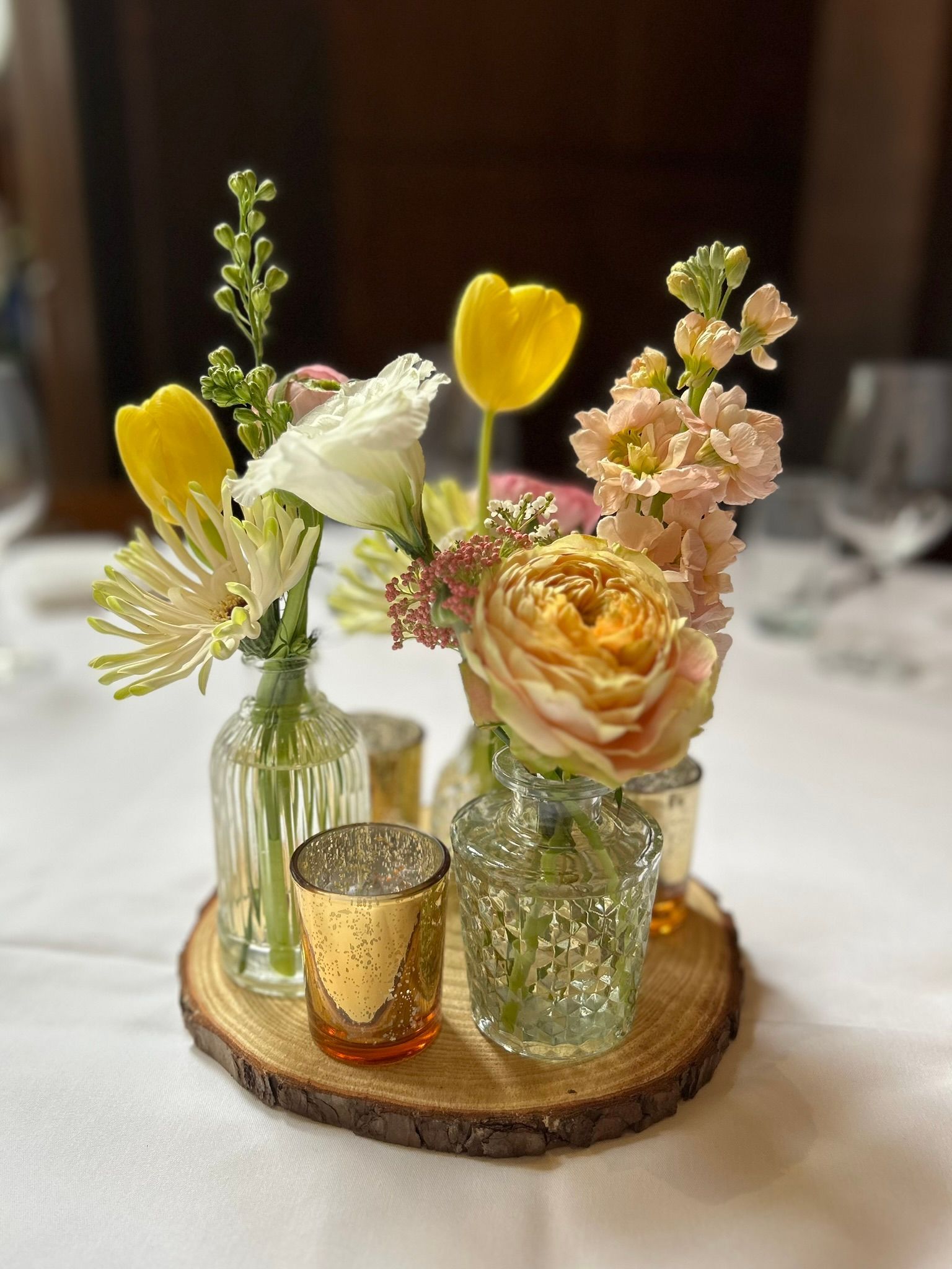 A table topped with vases filled with flowers and candles.