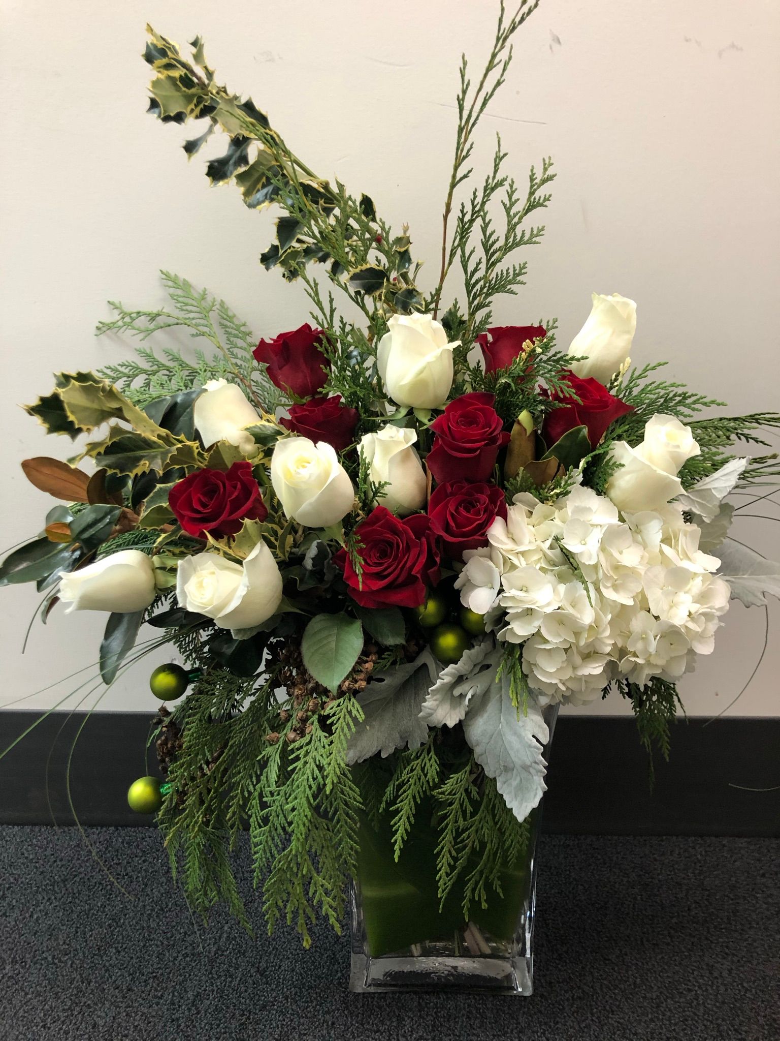 A vase filled with red and white flowers is sitting on the floor.