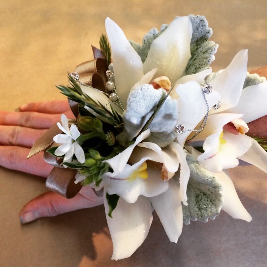 A woman is wearing a bouquet of white flowers on her wrist