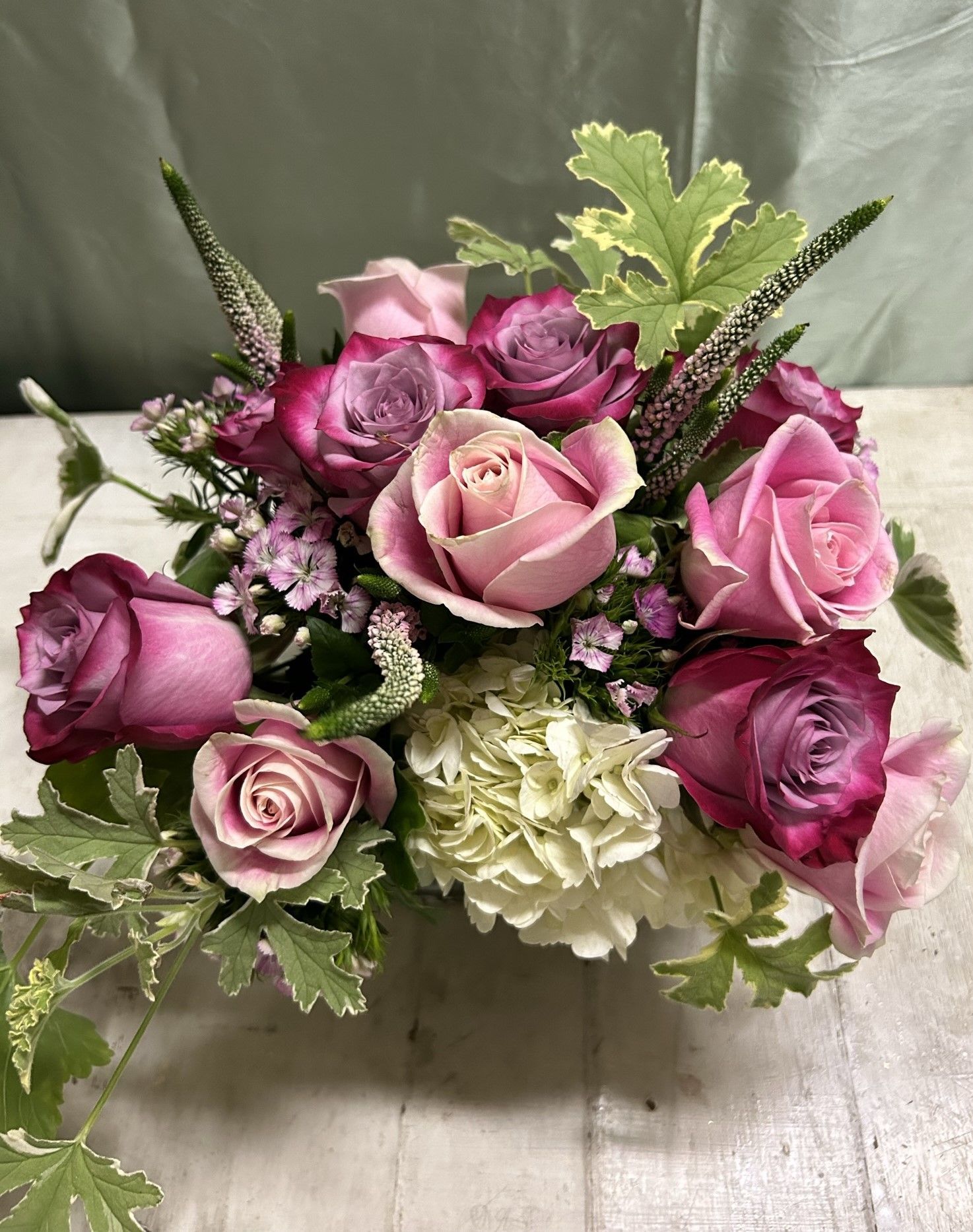 A bouquet of pink roses and white carnations is sitting on a table.