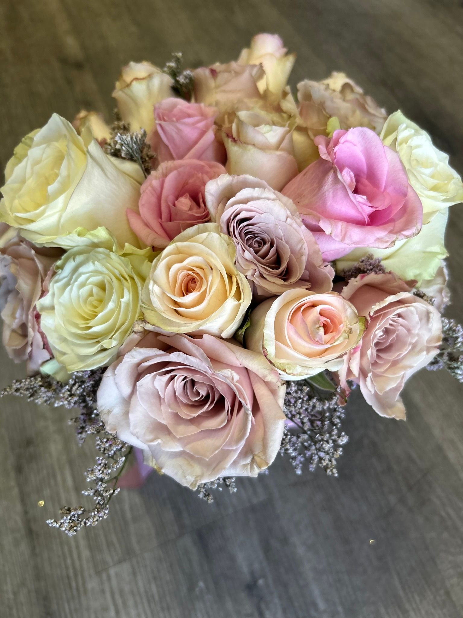 A bouquet of pink and white roses is sitting on a wooden table.