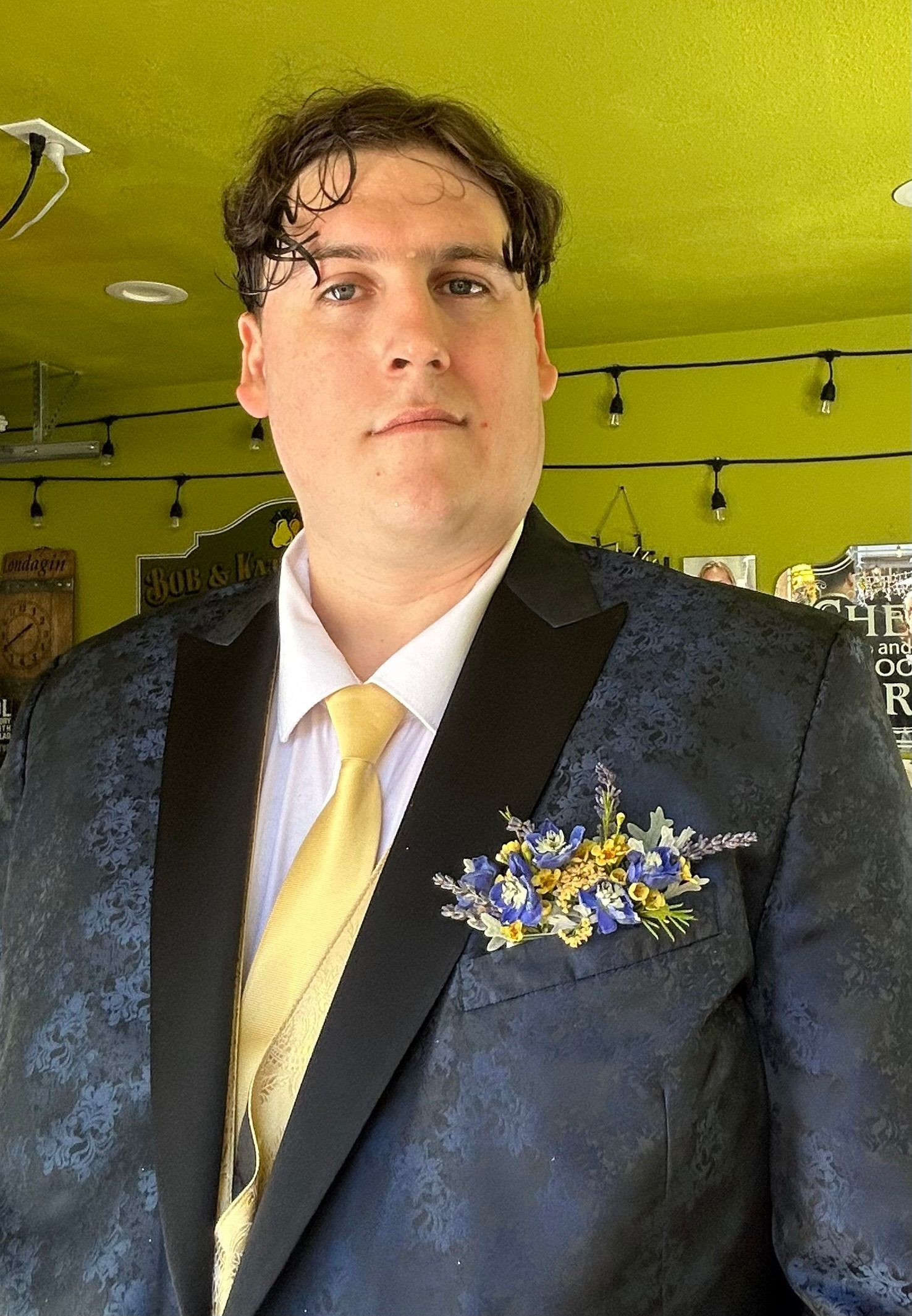 A man in a suit and tie is standing in front of a green wall.