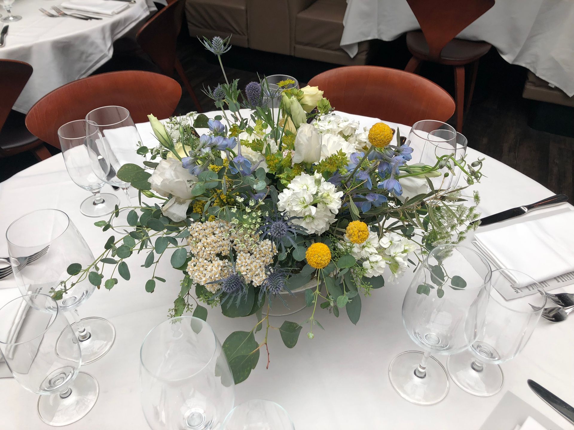 A table with a vase of flowers and wine glasses on it.