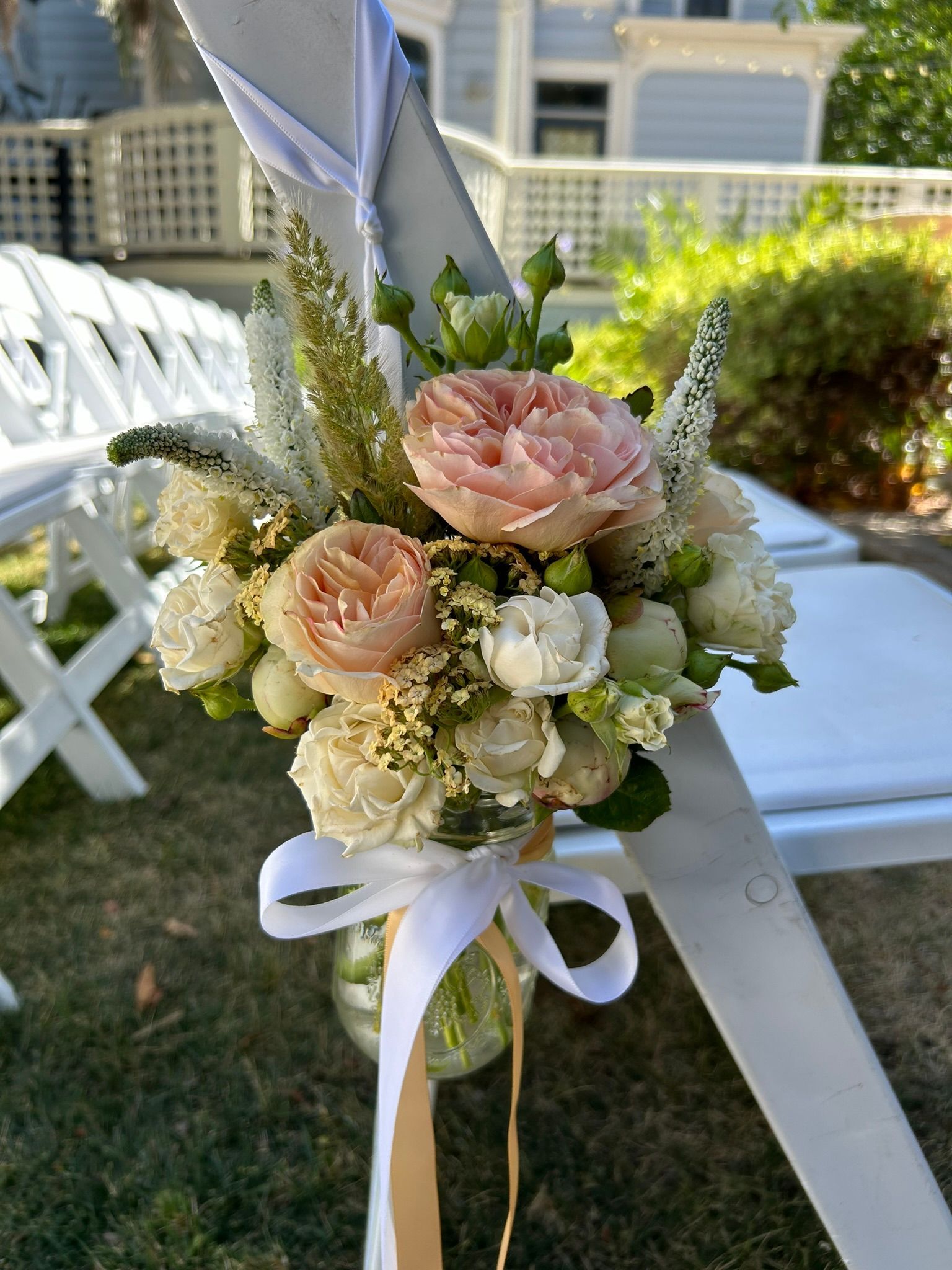 A mason jar filled with peach and white flowers for the aisle chairs.