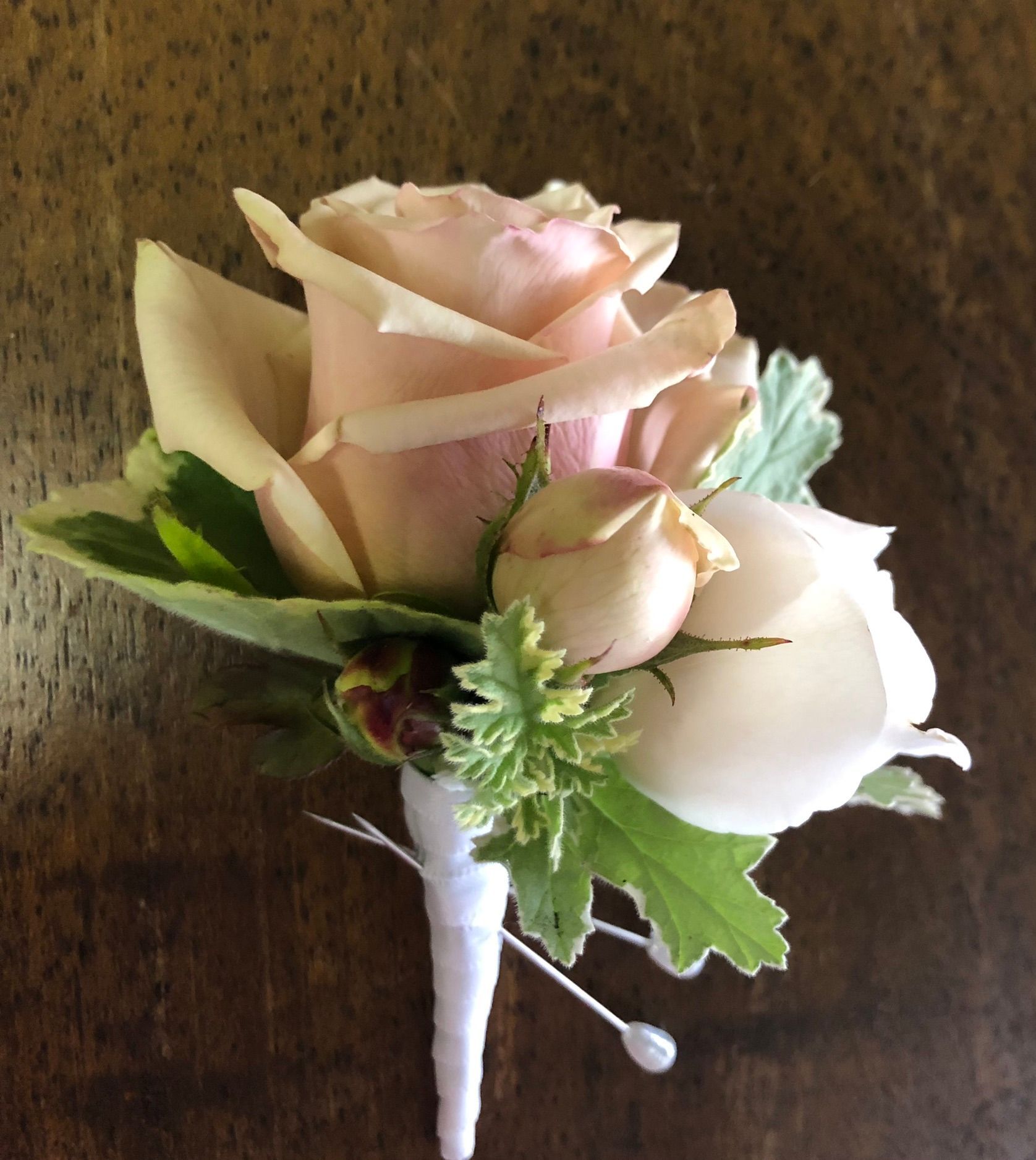 A pink rose with green leaves on a wooden table