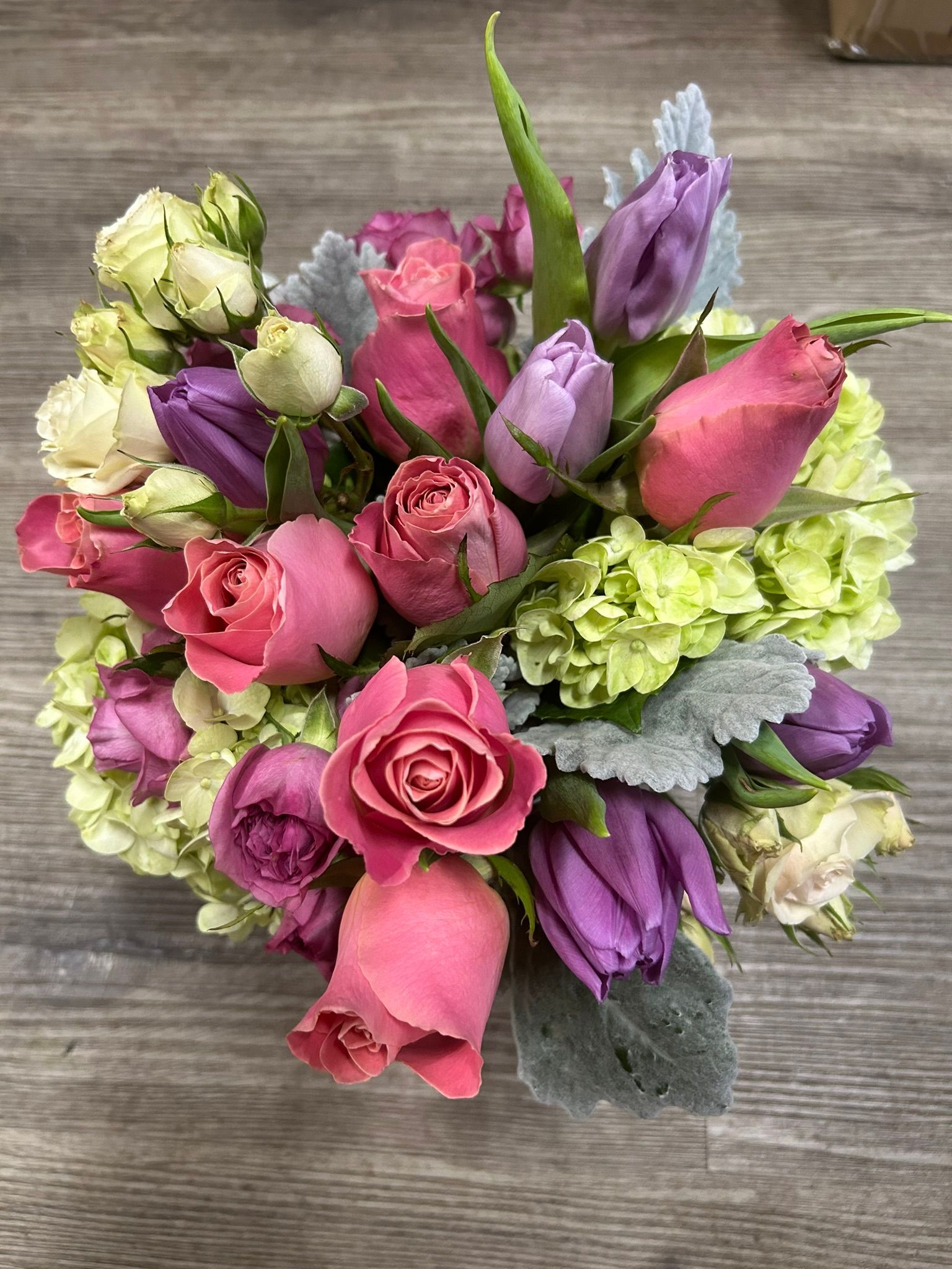 A bouquet of pink and purple roses with tulips and hydrangeas