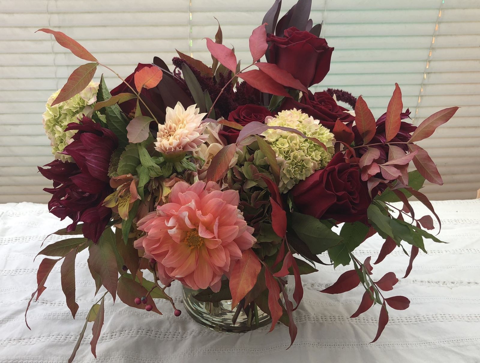 A vase filled with flowers and leaves on a table