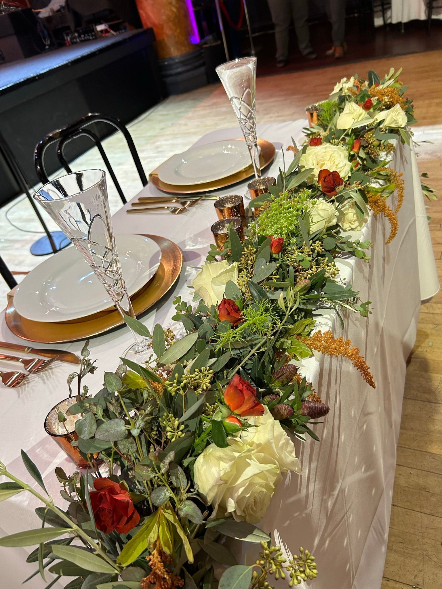 A long table with plates , glasses , and flowers on it.