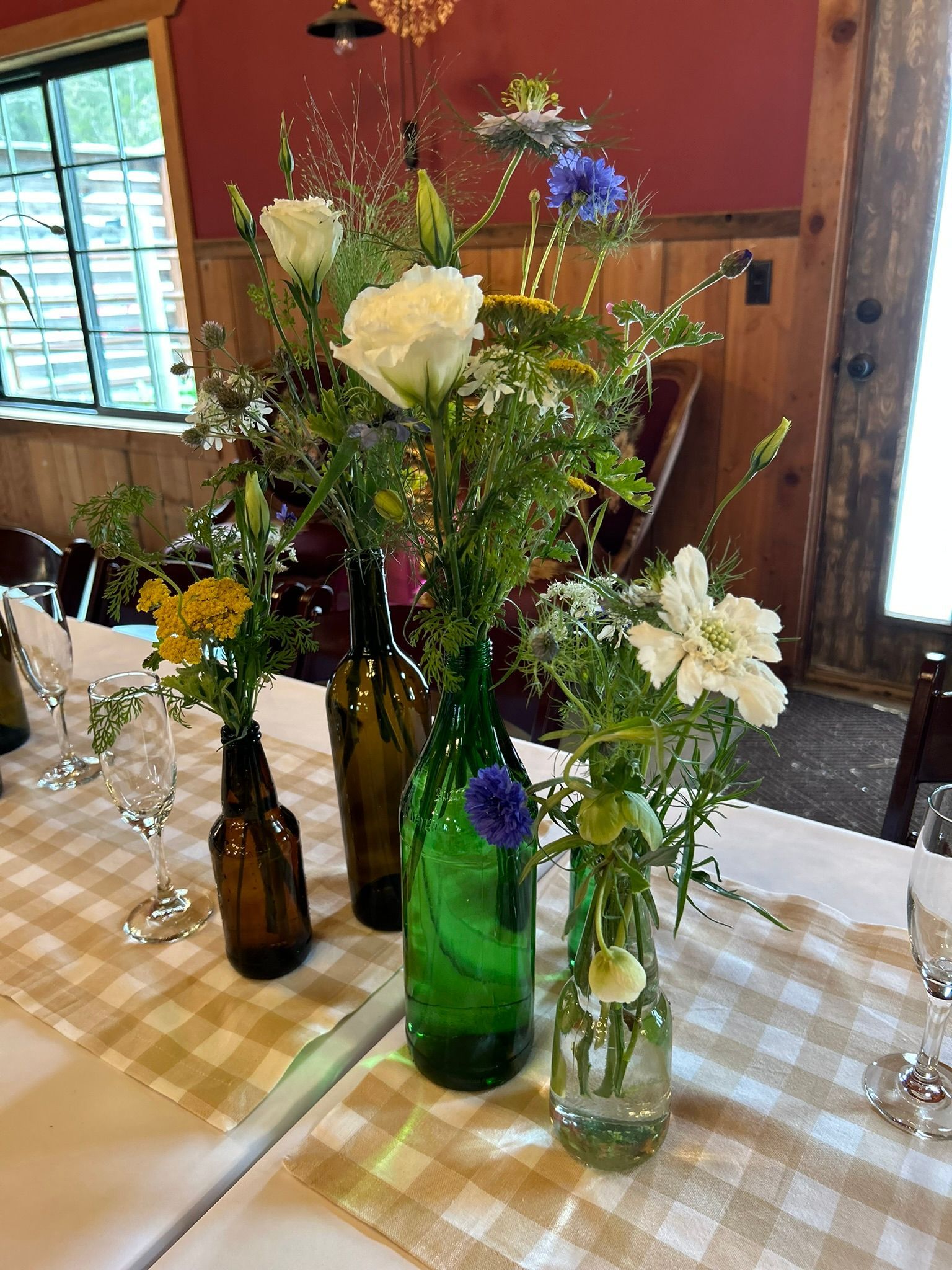A table with bottles and vases filled with flowers on it.