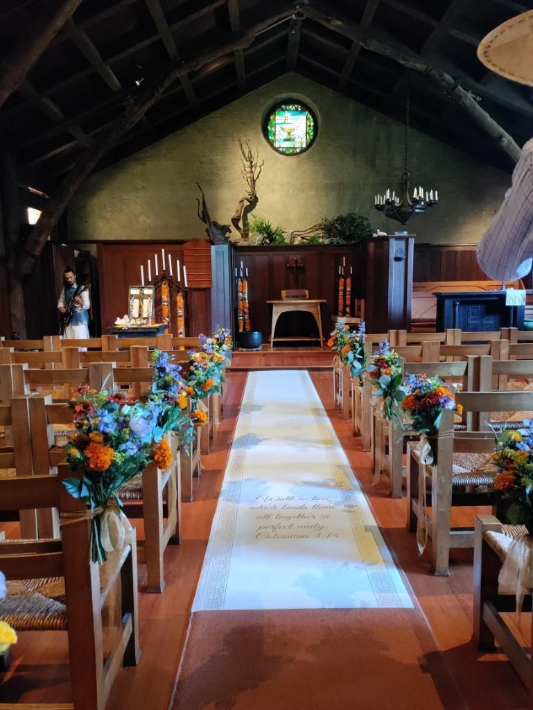 The aisle of a church is decorated with wildflowers.