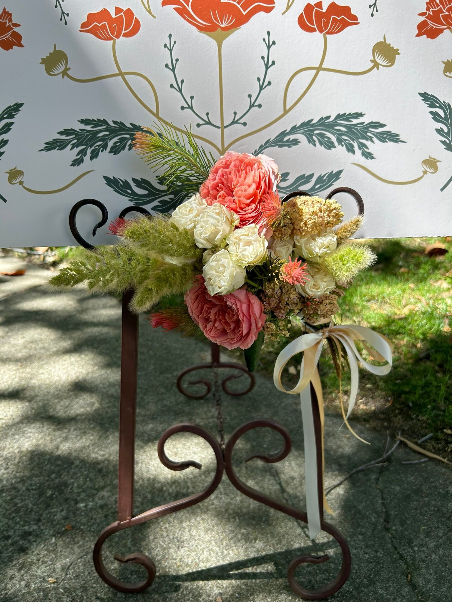 A bouquet of flowers is sitting on a wrought iron stand