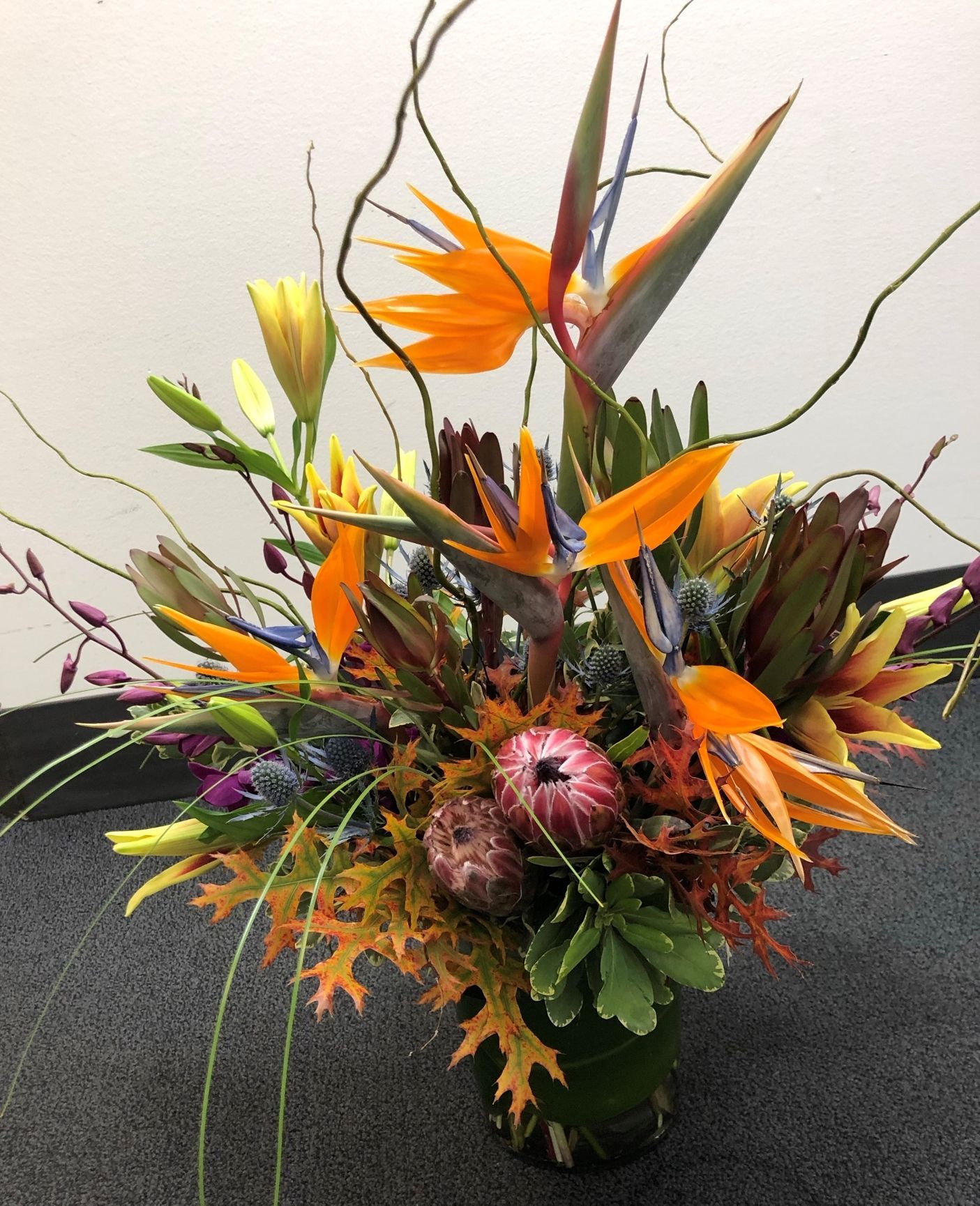 A tropical flower arrangement designed with birds of paradise, lilies and branches
