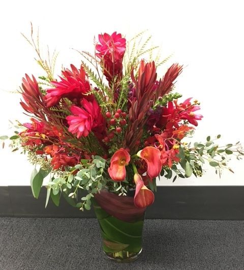 A vase filled with red flowers and greenery