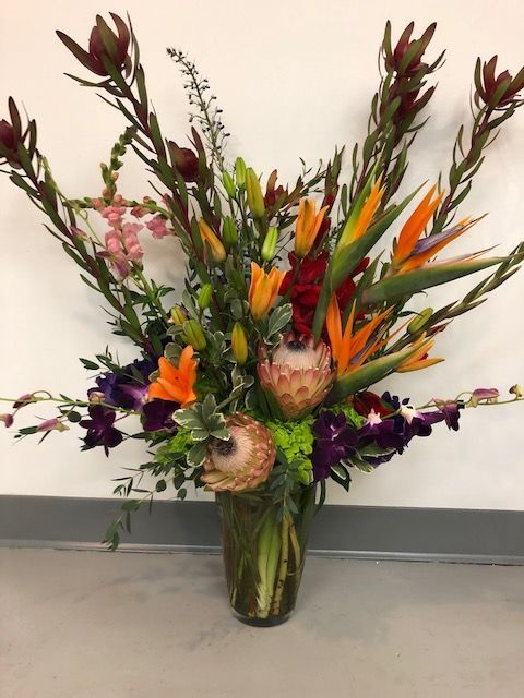 A vase filled with orange and burgundy flowers