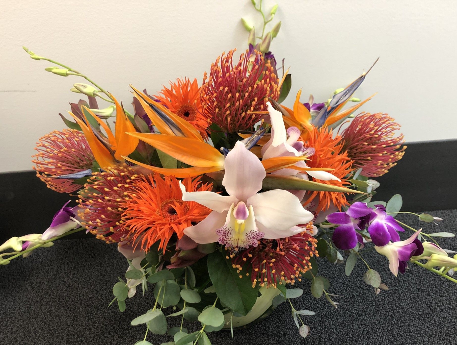 A vase filled with flowers is sitting on the floor.