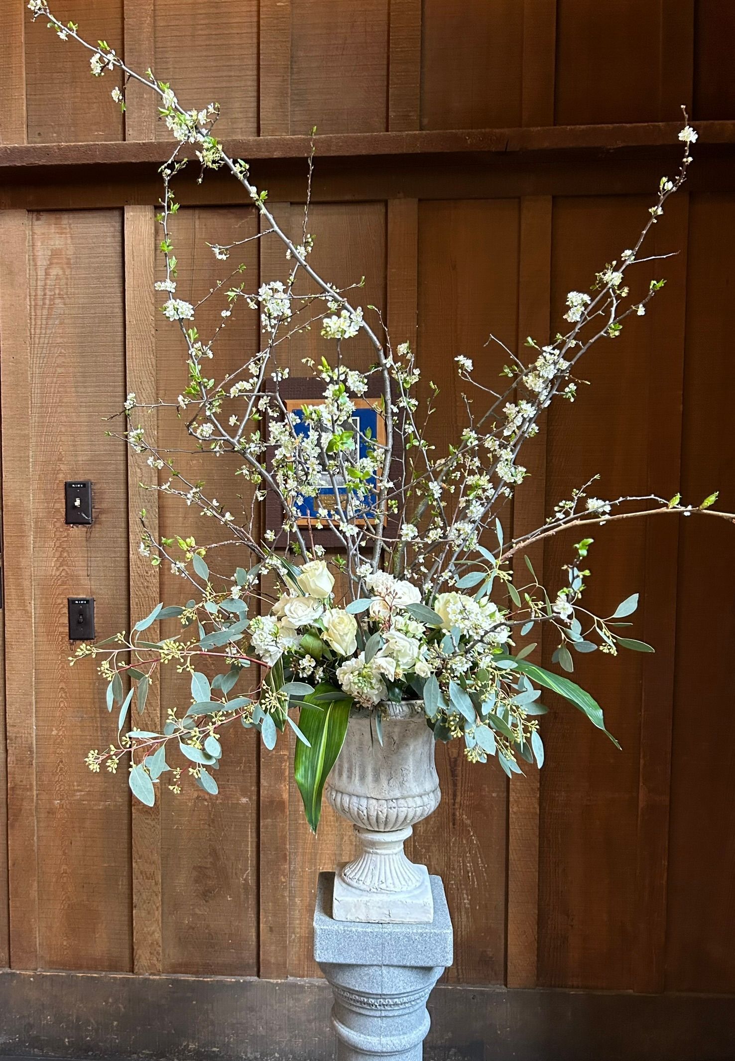 An urn filled with white flowers is sitting on a pedestal.