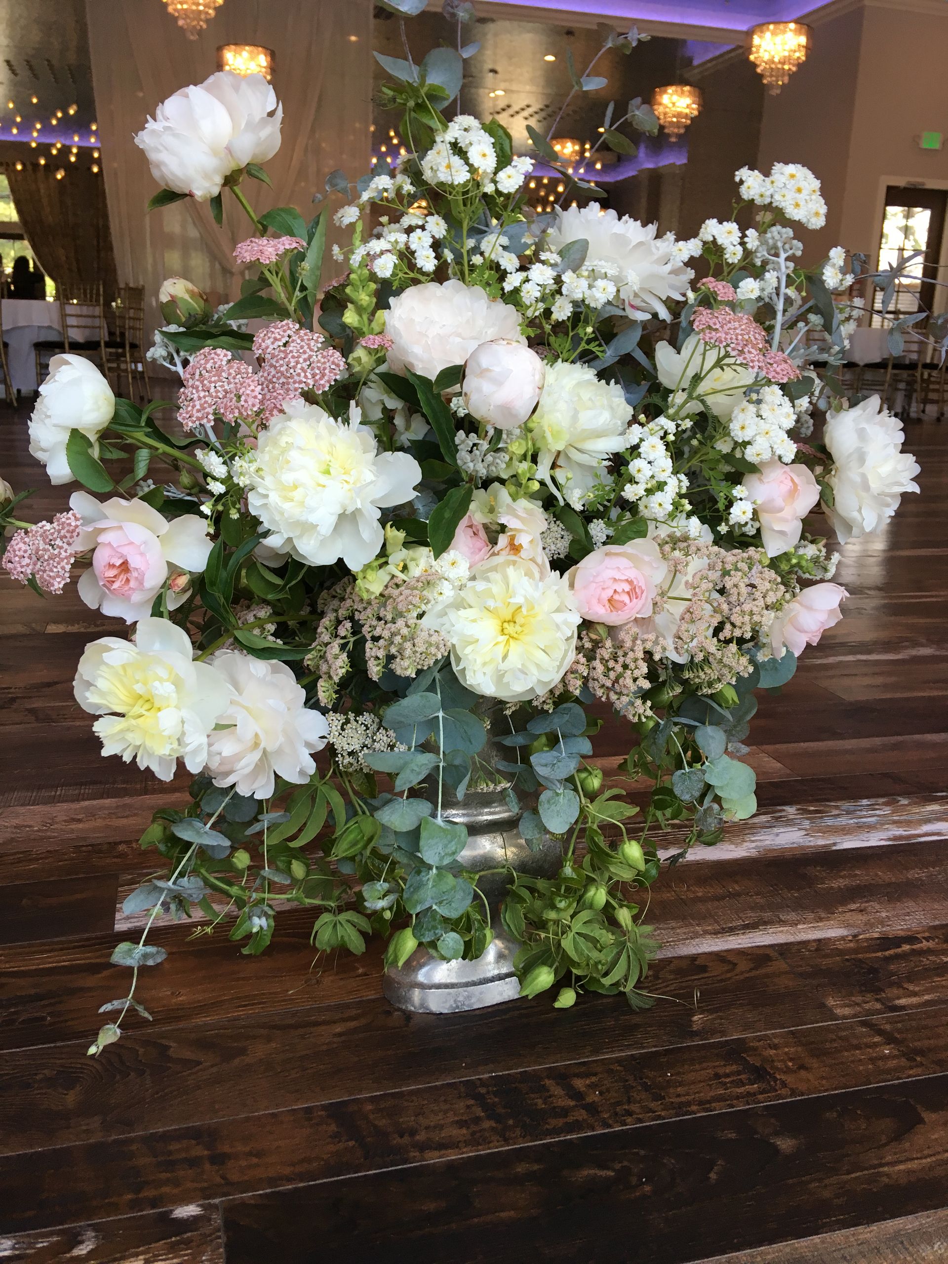 A silver vase filled with white and pink garden roses and seasonal flowers.
