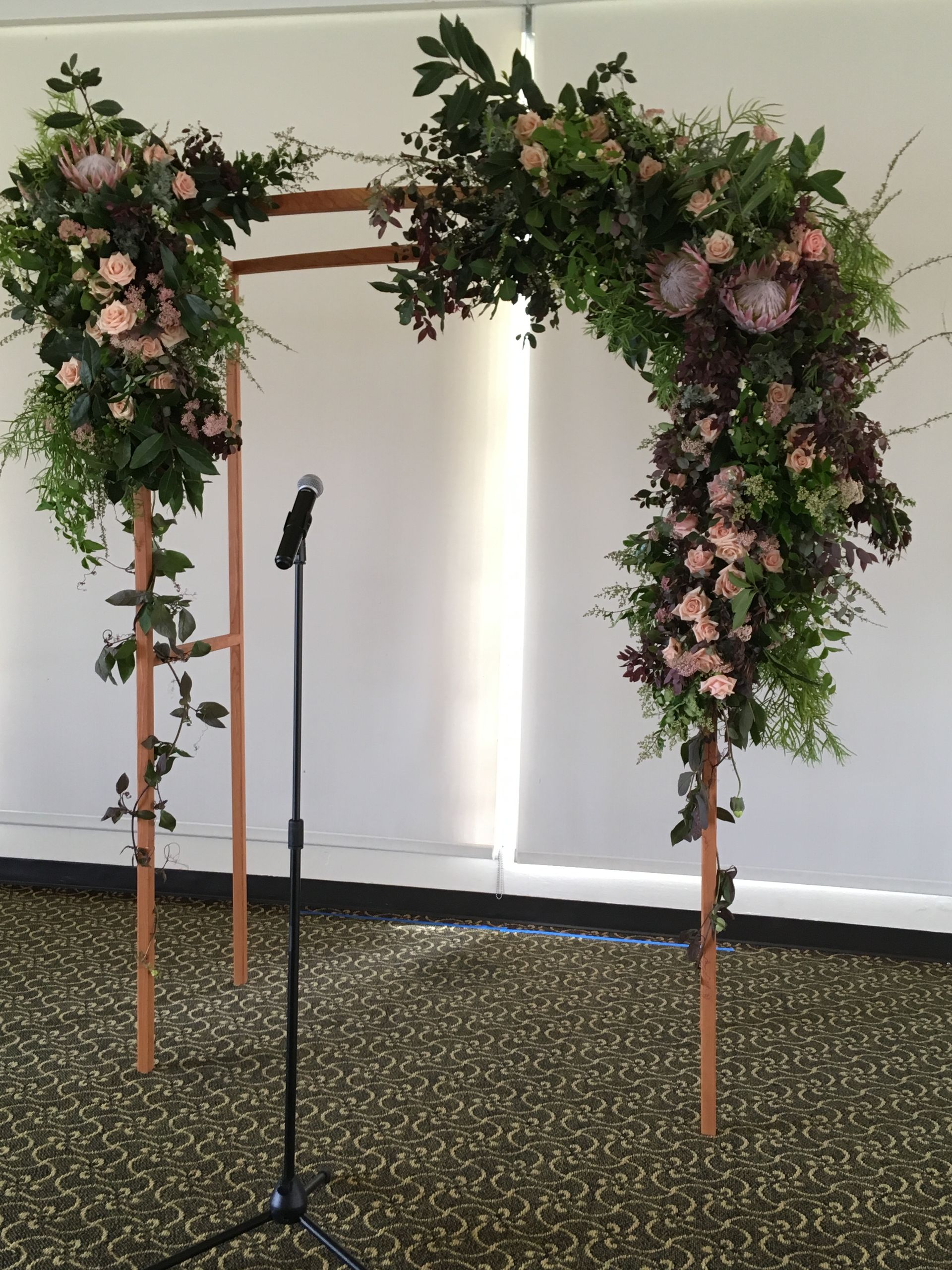 A wooden arch with dramatic and modern flower display and foliage