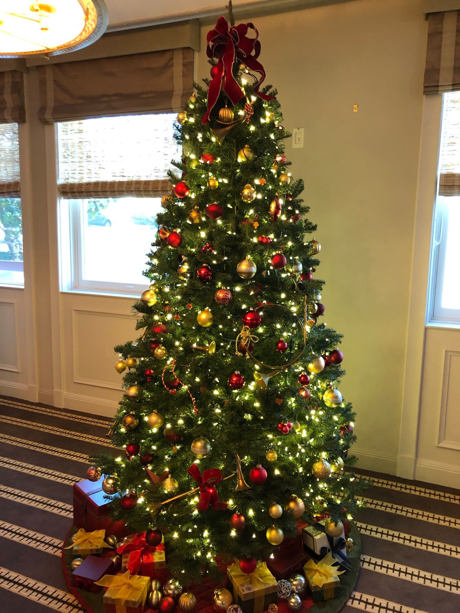A christmas tree is decorated with red and gold ornaments and lights.