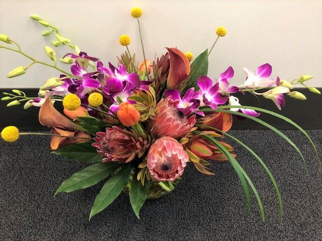 A bouquet of flowers is sitting on the floor in front of a wall.