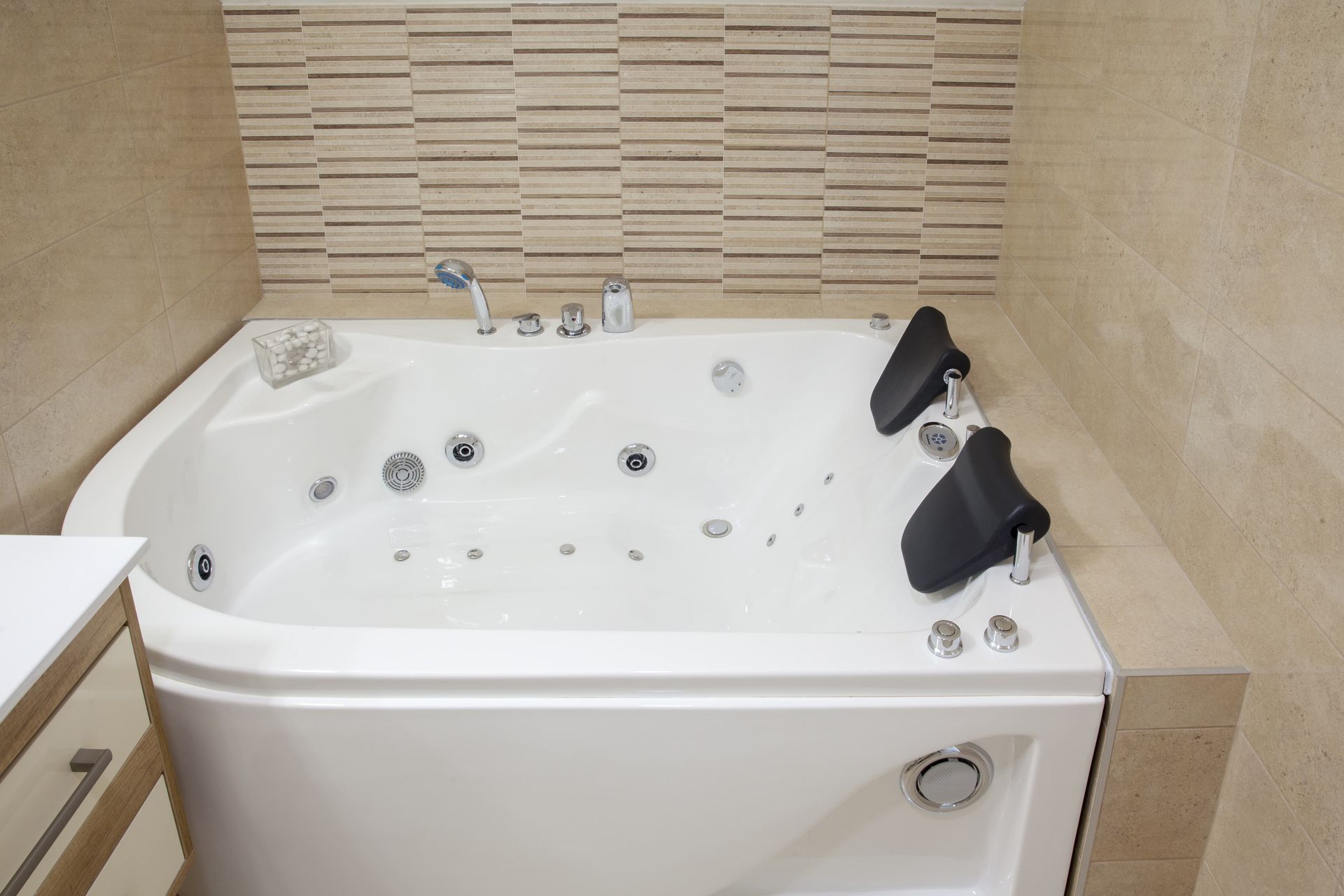 White corner jacuzzi tub with beige tile wall in a bathroom.