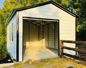 a white garage with a black trim and a fence in front of it