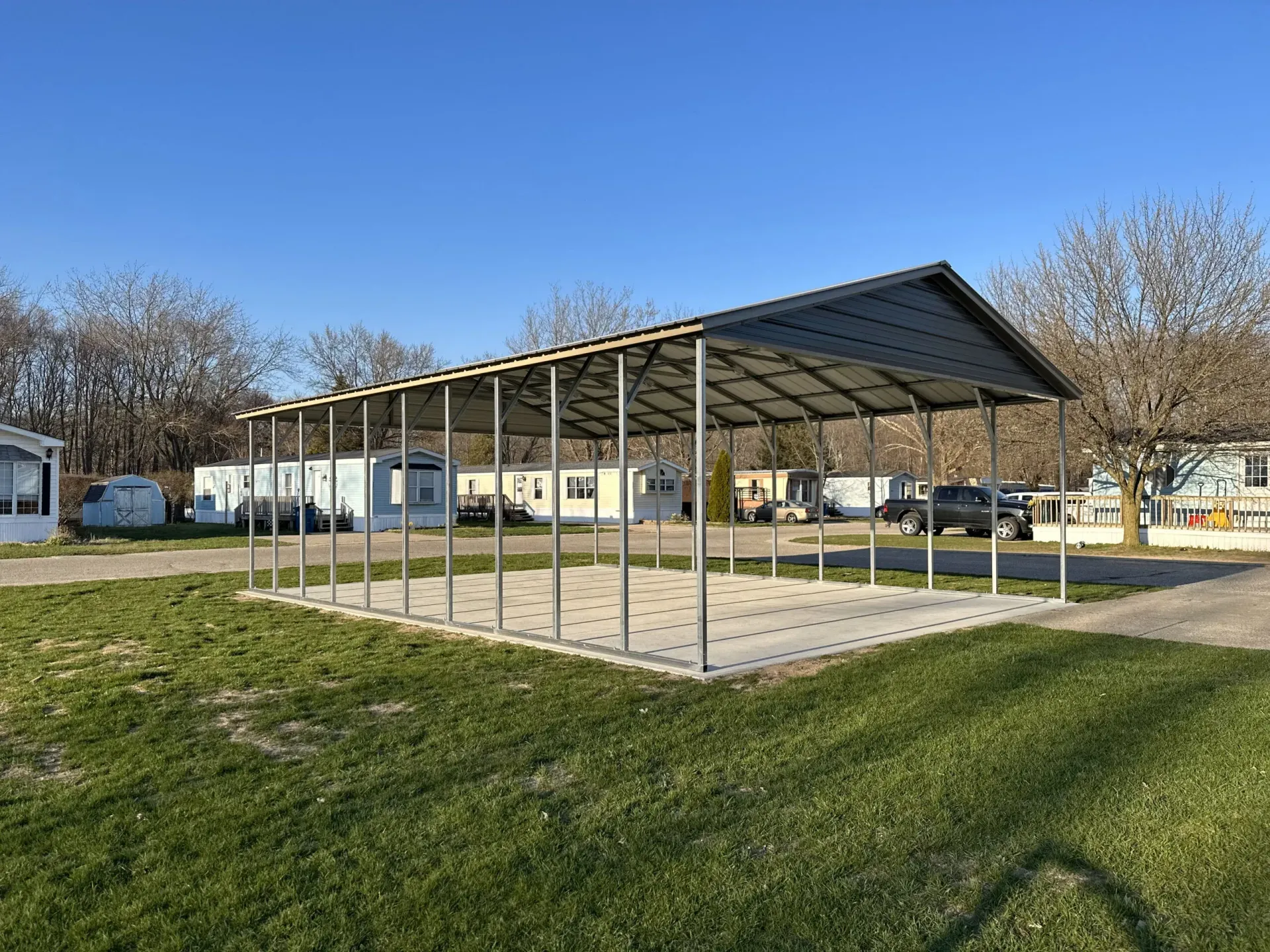 a metal carport is sitting in the middle of a grassy field