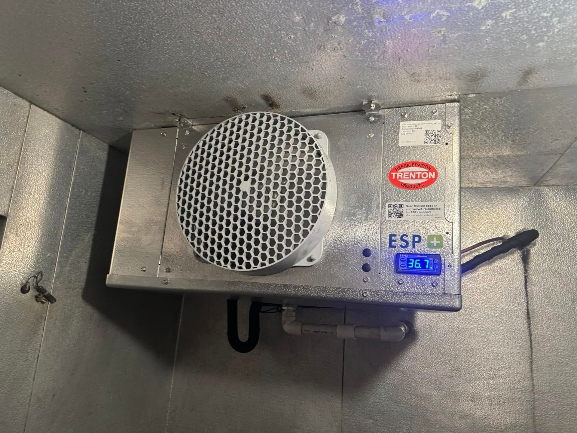 An industrial refrigeration unit mounted on a silver wall displays temperature; ESP label visible.