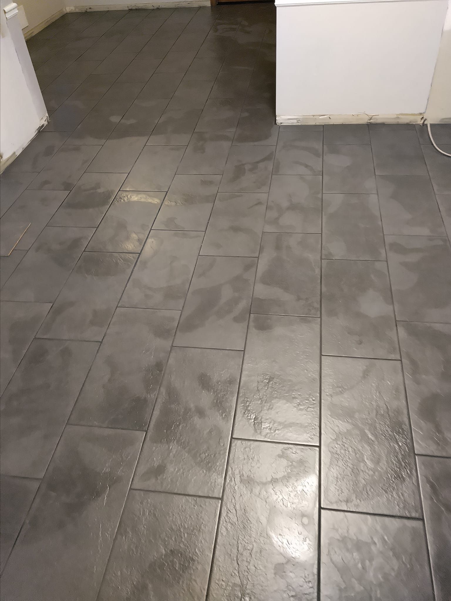 Dark gray rectangular tiles cover a floor.