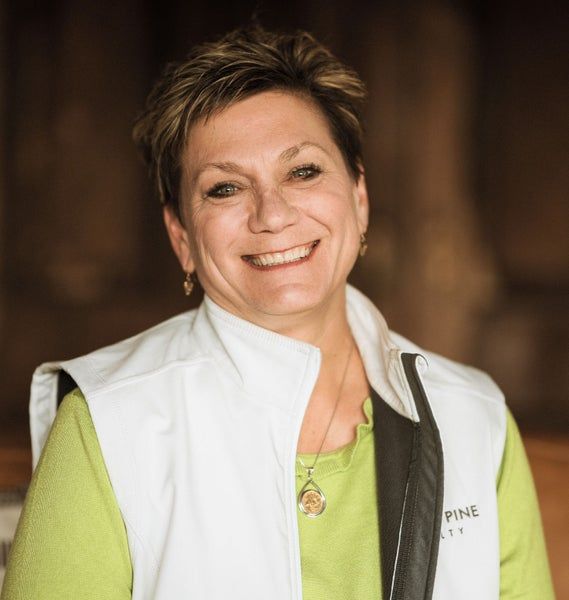 A woman wearing a white vest that says pine on it