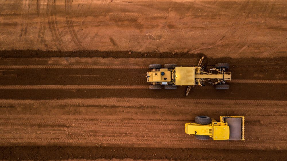 An Aerial View Of Two Yellow Tractors Working On A Dirt Road — Arnway Pty Ltd In Macksville, NSW
