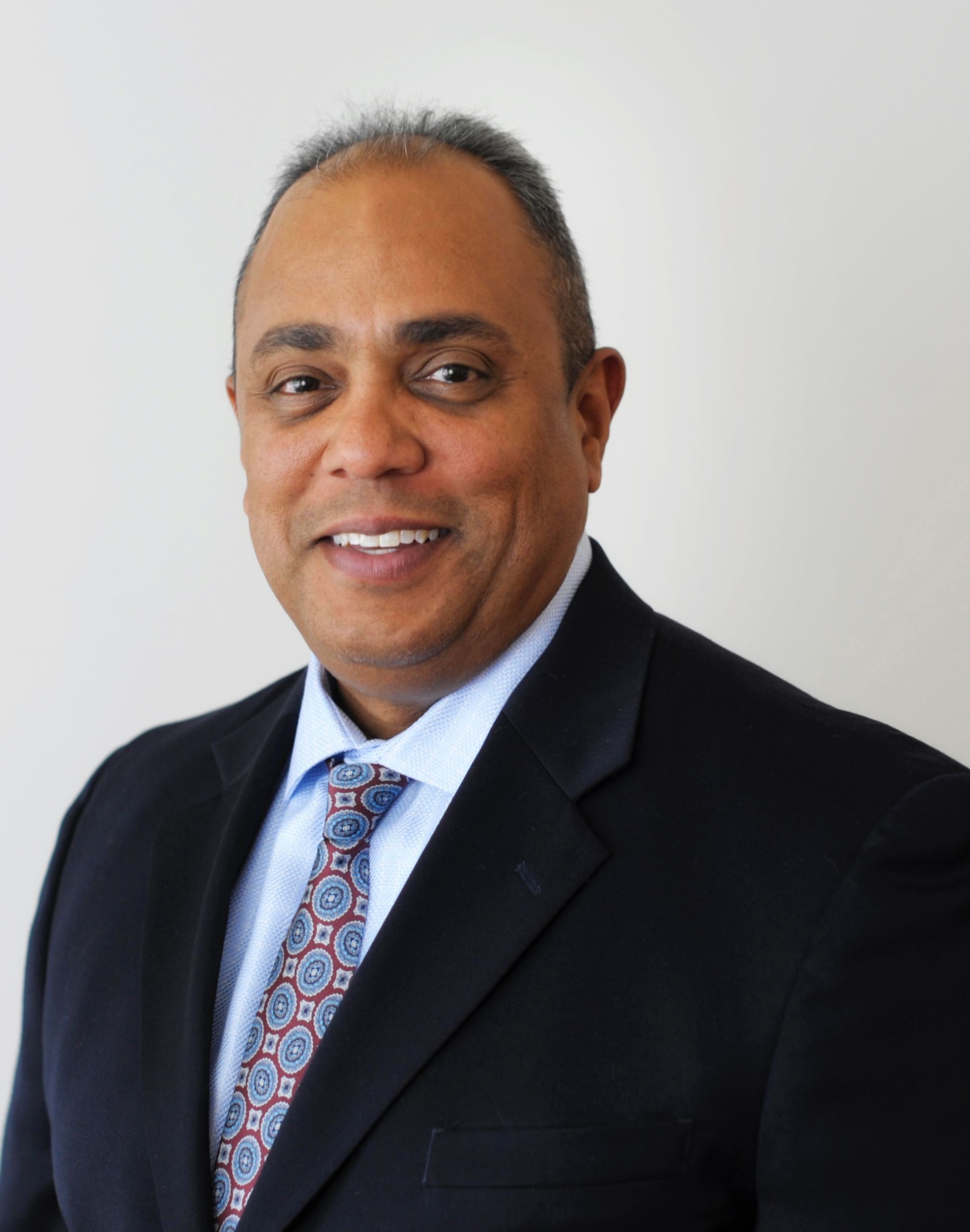 A man in a suit and tie is smiling for the camera