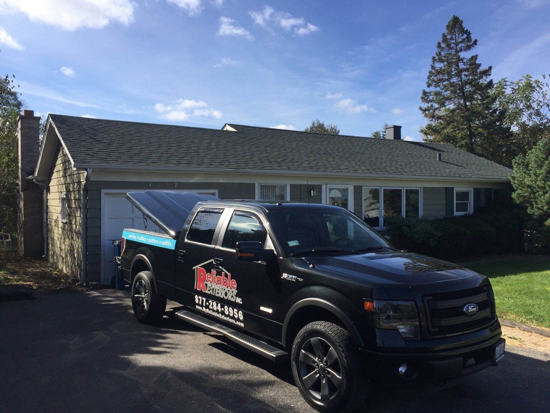 A black truck is parked in front of a house.