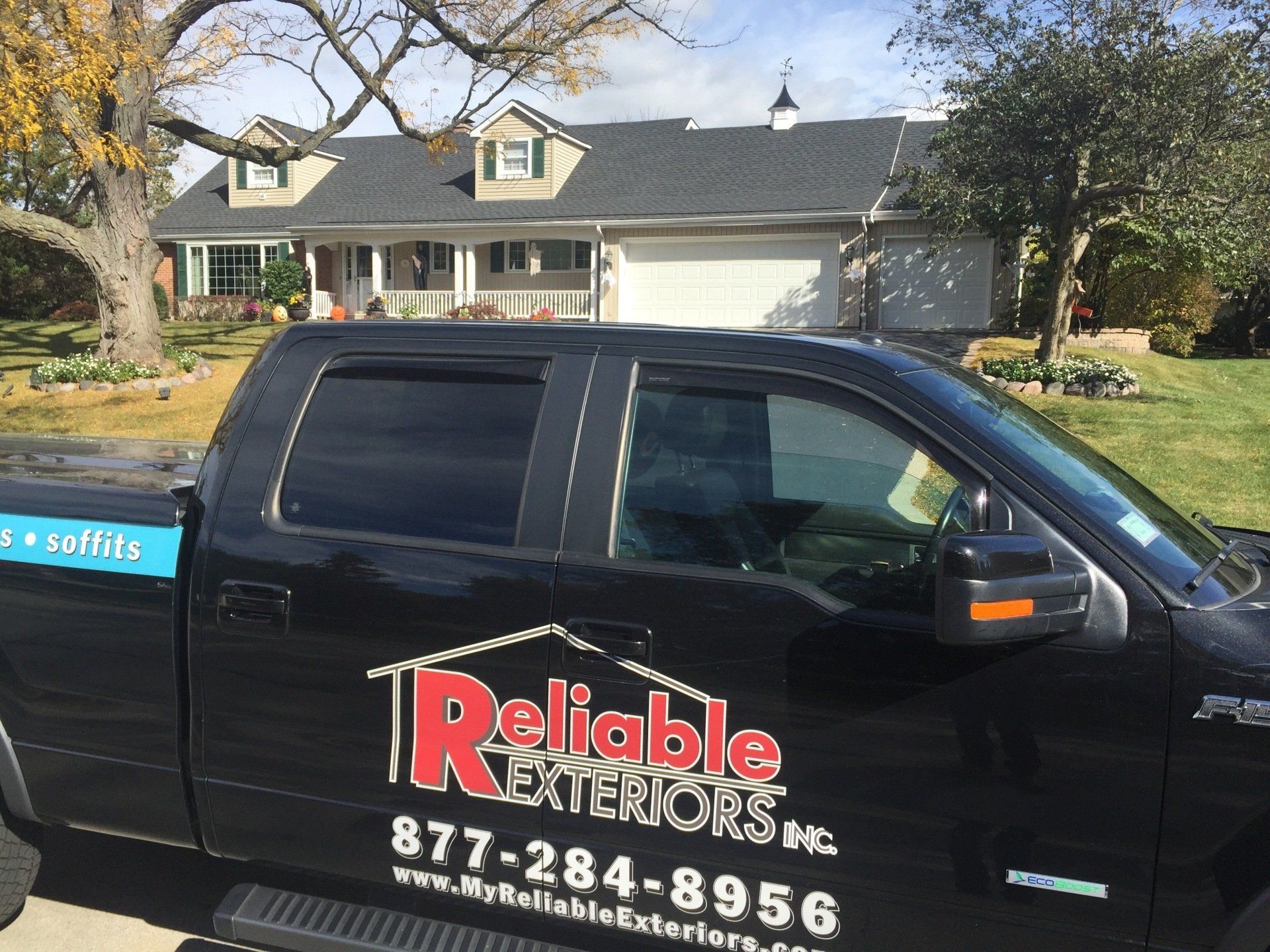 A reliable exteriors truck is parked in front of a house