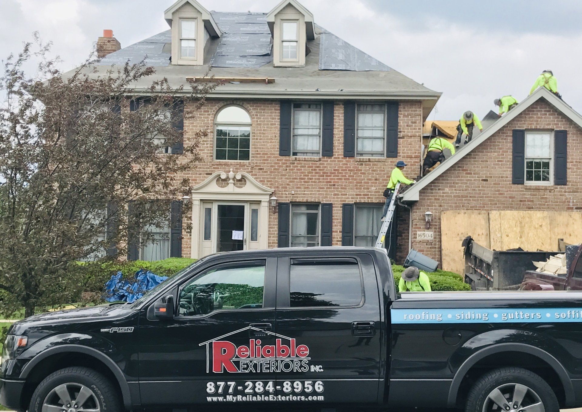 A black truck is parked in front of a large brick house.