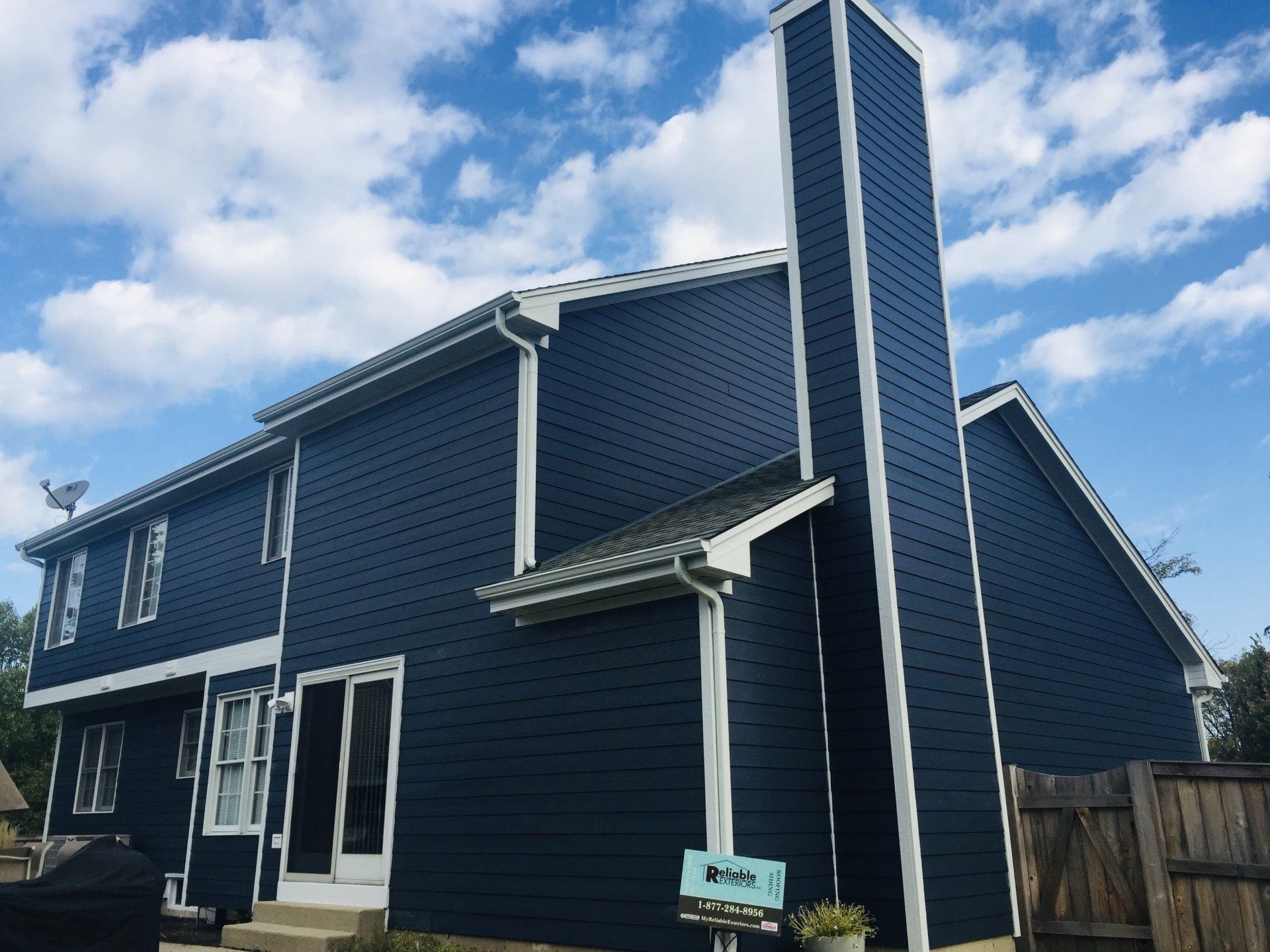 A large blue house with a chimney on the side of it.