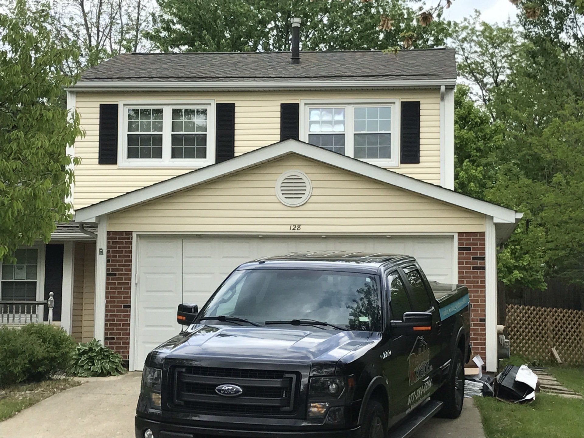 A black ford truck is parked in front of a house