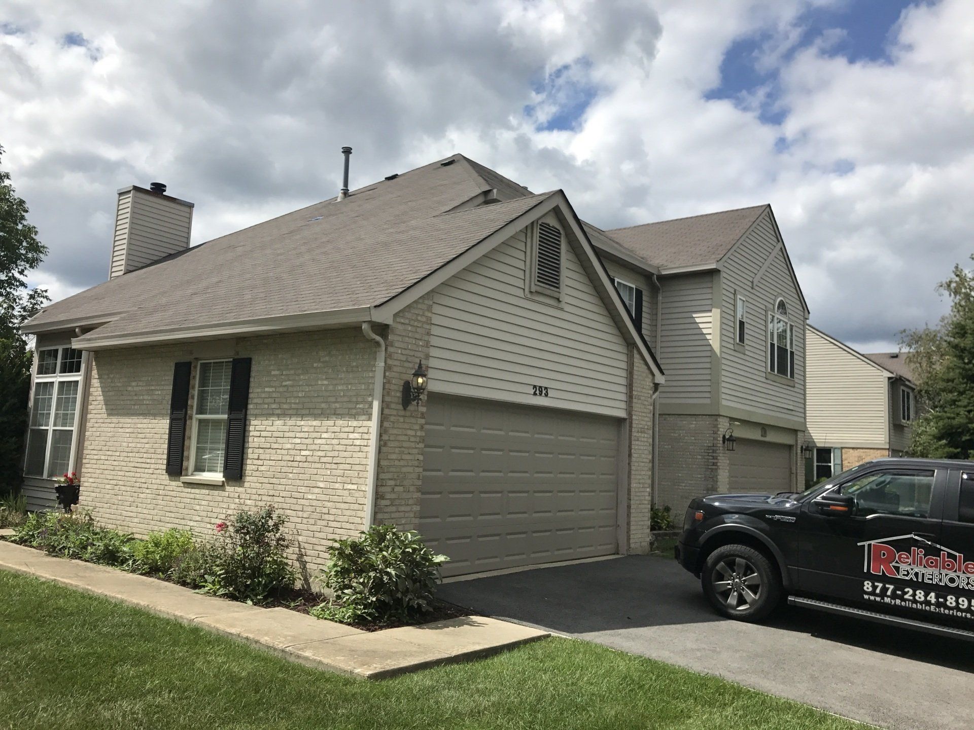 A truck is parked in front of a brick house.